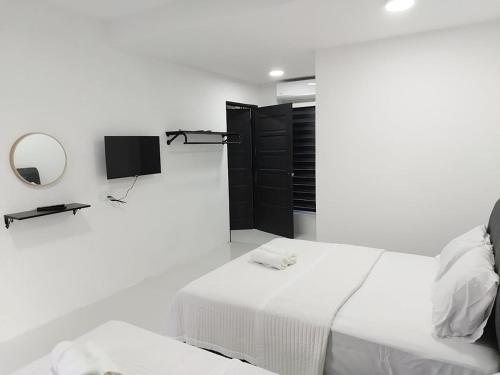 a white bedroom with a bed and a tv at Afeeya The Roomstay in Kuala Terengganu