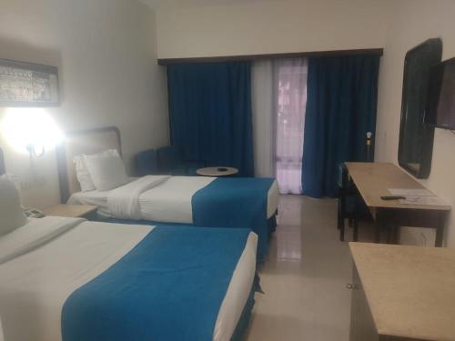 a hotel room with two beds and a desk at Aracan Eatabe Luxor Hotel in Luxor