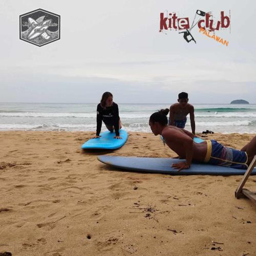 a group of people sitting on surfboards on the beach at Surf and Skate Duli El Nido By Kiteclub Palawan in El Nido