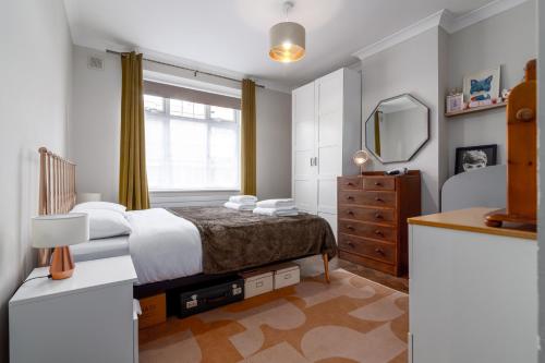 Schlafzimmer mit einem Bett, einer Kommode und einem Spiegel in der Unterkunft Central London 1 BR Apt in Vauxhall near Big Ben in London