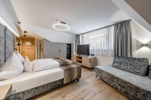 a bedroom with a bed and a couch and a television at Hotel Grauer Bär in Sölden