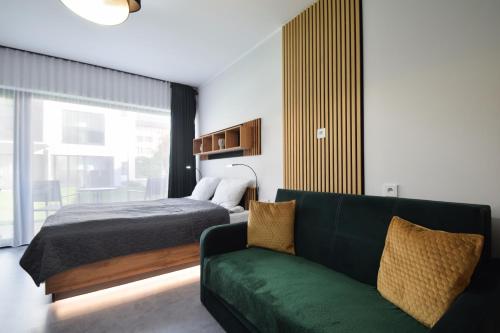 sypialnia z łóżkiem i zieloną kanapą w obiekcie Apartament Royal Solny Resort z aneksem kuchennym w hotelu z krytym basenem, sauną i usługami SPA w Kołobrzegu