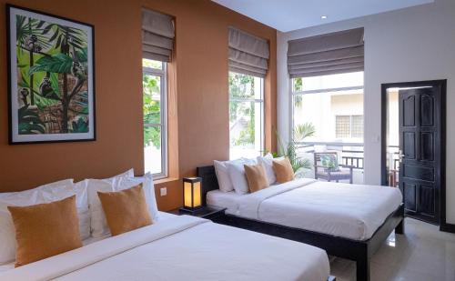 2 Betten in einem Zimmer mit 2 Fenstern in der Unterkunft Babel Boutique in Siem Reap