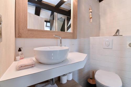 uma casa de banho branca com um lavatório e um WC em Jaennette em Ribeauvillé