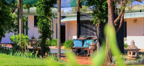 a house with a table and a chair in the yard at Oasis Motel in Peak Hill
