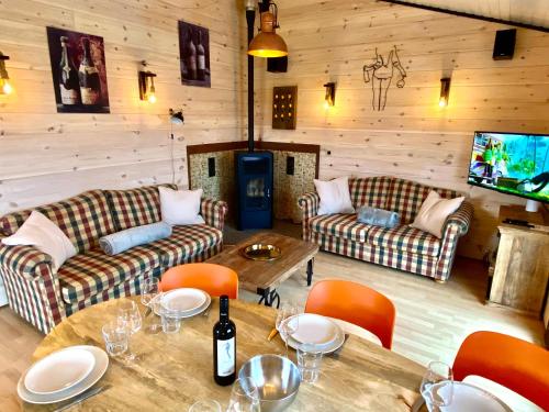 a living room with couches and tables and a tv at Au Chalet du Lac in Bullange