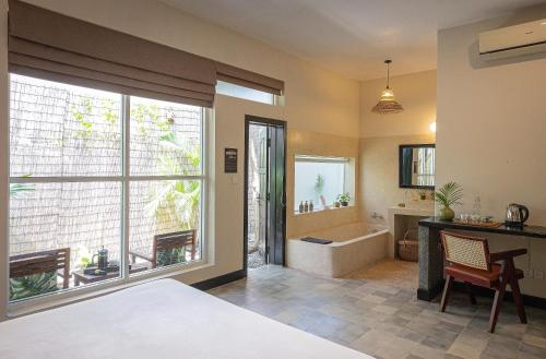 a bedroom with a bed and a bathroom with a tub at Babel Boutique in Siem Reap