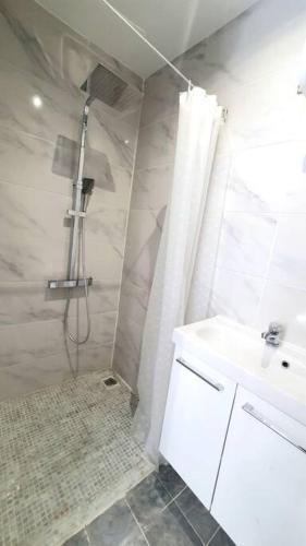 une salle de bain blanche avec une douche et un lavabo dans l'établissement Appartement Hypercentre 203 + WIFI +INDEPENDANT+TOILETTE CUISINE SALLE DE BAIN PRIVATIVE, à Valenciennes
