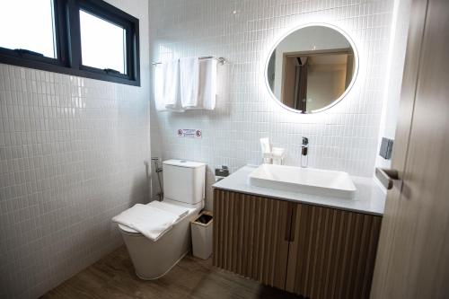 a bathroom with a toilet and a sink and a mirror at The Arch Phuket Hotel in Ban Ket Ho