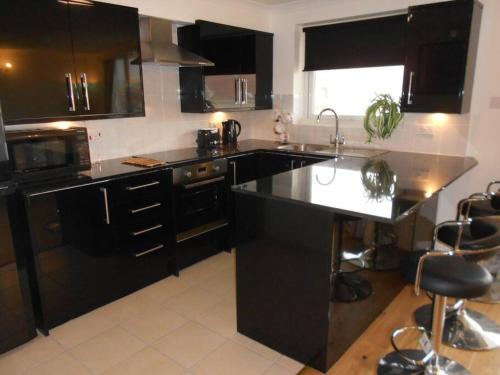 cocina con armarios negros y encimera negra en BOURNECOAST: Stunning apartment on clifftop-FM4967, en Southbourne