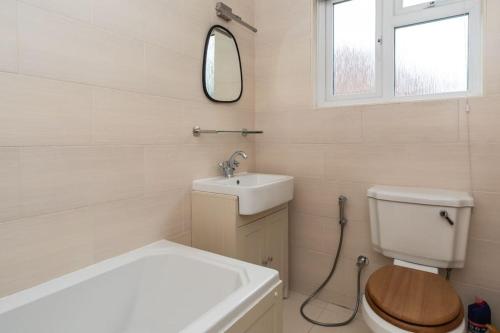 Un baño con lavabo, inodoro y espejo. en Luxurious 4-Bed Holiday Retreat, en Finchley