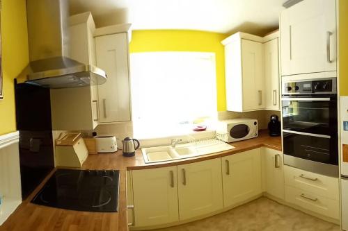 a kitchen with white cabinets and a sink and a window at The Side - Hexham in Hexham