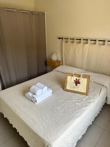 ein Bett mit zwei Handtüchern und einer Schachtel darauf in der Unterkunft Grand appartement T4, piscine, vue exceptionnelle à 50 m de la plage in Propriano
