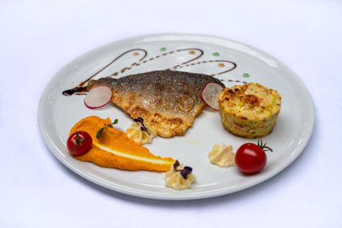 a plate of food with a piece of fish and fruit at Moulin de Vernègues Hôtel & Spa in Mallemort