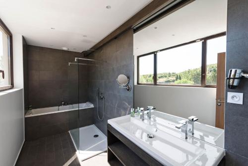 a bathroom with a sink and a shower and a tub at Moulin de Vernègues Hôtel & Spa in Mallemort