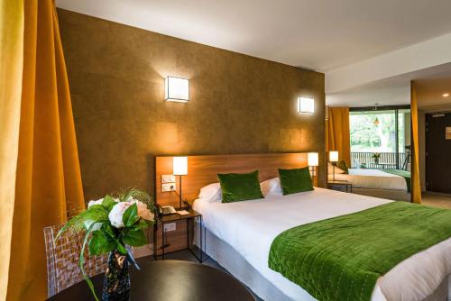 a bedroom with a large bed with a green blanket at Moulin de Vernègues Hôtel & Spa in Mallemort