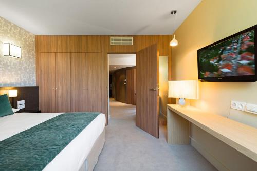 a hotel room with a bed and a flat screen tv at Moulin de Vernègues Hôtel & Spa in Mallemort