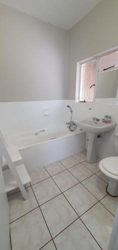 a bathroom with a tub and a sink and a toilet at Blue Door in Boksburg