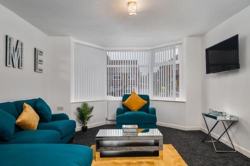 a living room with two blue chairs and a tv at Borrowdale Brook in Leeds