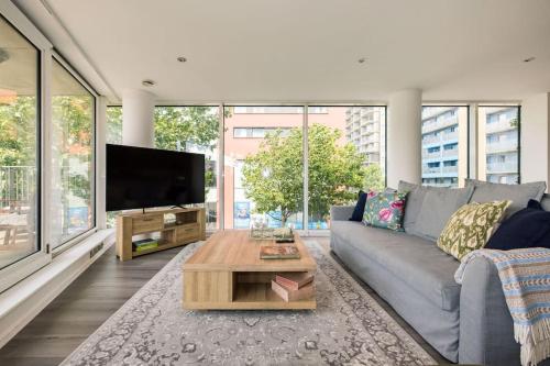 a living room with a gray couch and a tv at ExCel London Spacious 3 Bedroom - Royal Docks in London
