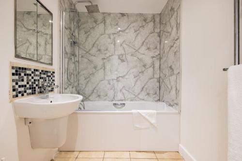Convenient - ExCel London - O2- 3 Bedroom Apartment في لندن: حمام أبيض مع حوض وحوض استحمام ومرحاض