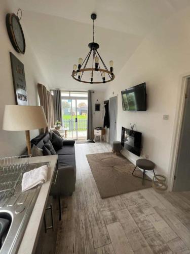 a living room with a couch and a chandelier at Stunning One Bed Modern & Contemporary Chalet in Bridlington