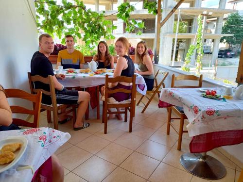 un groupe de personnes assises à une table dans un restaurant dans l'établissement GuestHouseMantho, à Gjirokastër