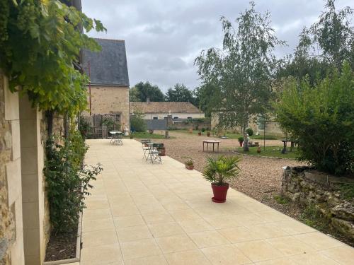 a patio with a table and chairs in a yard at LE PRESBYTERE in Rouperroux-le-Coquet