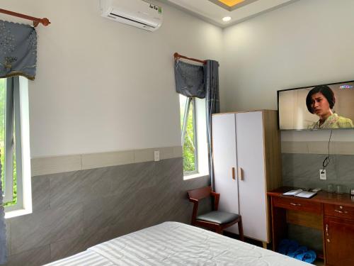 - une chambre avec un lit et une télévision murale dans l'établissement Khách Sạn An Bình, à Phước Lộc Xã