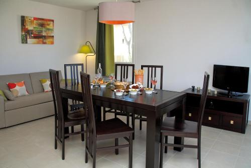 a dining room table with chairs and a television at Lagrange Vacances Les Terrasses des Embiez in Six-Fours-les-Plages