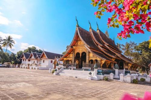 a large building with a pointed roof in a courtyard at QUEEN'S HOUSE in Luang Prabang