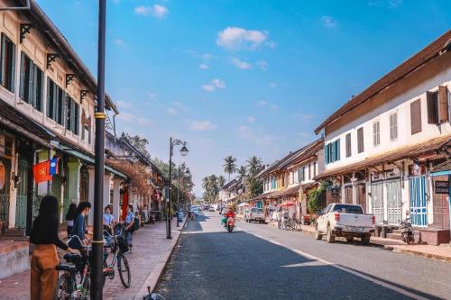 a city street with people riding bikes on the street at QUEEN'S HOUSE in Luang Prabang