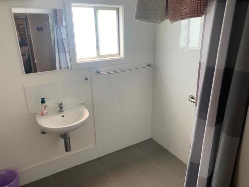 bagno bianco con lavandino e specchio di Blue Sapphire Village 3 Bedroom a Glen Innes