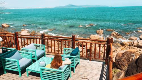 a woman sitting on a deck looking at the ocean at Resort Bai Xep Quy Nhon in Quy Nhon