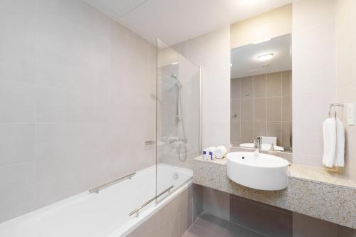 uma casa de banho branca com um lavatório e um chuveiro em Maison Privee - Elegant & Panoramic Sea View Apt on Al Reem Island em Abu Dhabi