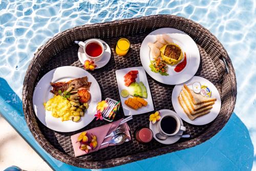 un vassoio di prodotti per la colazione su un tavolo accanto alla piscina di Luxotic Private Villa and Resort a Nusa Dua