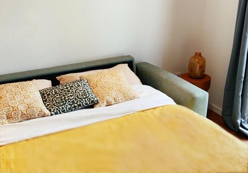 a bed with a yellow blanket and pillows on it at Le Studio Design ⸱ Stationnement gratuit ⸱ Fibre in Déols