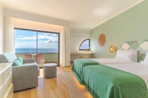 a bedroom with a large bed and a large window at Pestana Vila Lido Madeira Ocean Hotel in Funchal