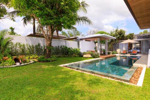 un patio trasero con piscina y una casa en Luxury villa with pool and garden - BL #93, en Phuket