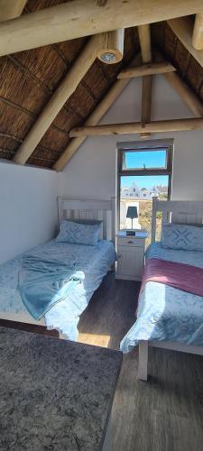 2 camas en una habitación con ventana en Serenity Jaconsbaai, en Jacobs Bay