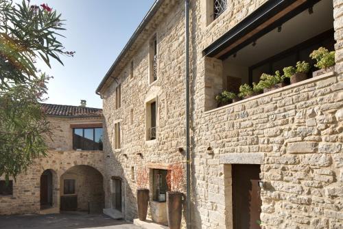 un antiguo edificio de ladrillo con plantas en las ventanas en La Maison du Passage - Chambres - Suites premium, Spa, Piscine et Restaurant, en Martignargues