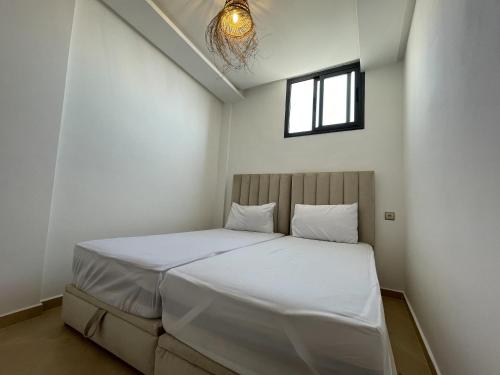 a bedroom with a bed with white sheets and a window at La Brise Studio à Taghazout 2-3px in Taghazout