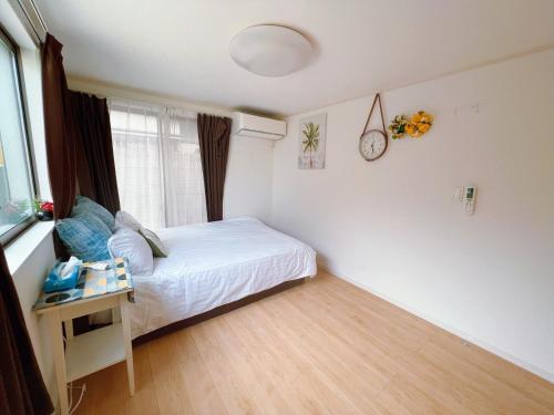 a bedroom with a bed and a table with a clock on the wall at JINGHOUSE高砂（無料駐車場）一戸建て 上野/浅草/银座/天空树 in Tokyo
