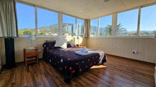 una camera con un letto in una stanza con ampie finestre di Benidorm B&B Albir a Albir