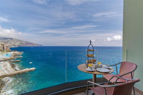 a table and two chairs in a room with a view of the ocean at Pestana Vila Lido Madeira Ocean Hotel in Funchal