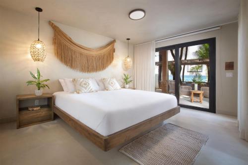 - une chambre avec un grand lit blanc et un balcon dans l'établissement Arca, à Roatán
