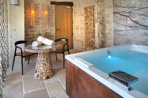 a large tub in a room with a table and chairs at La Maison du Passage - Chambres - Suites premium, Spa, Piscine et Restaurant in Martignargues
