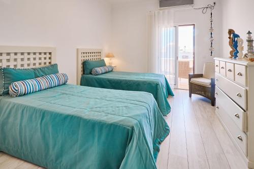 um quarto com 2 camas com lençóis verdes e uma cómoda em Casa da Praia mit Poolanlage em Porches