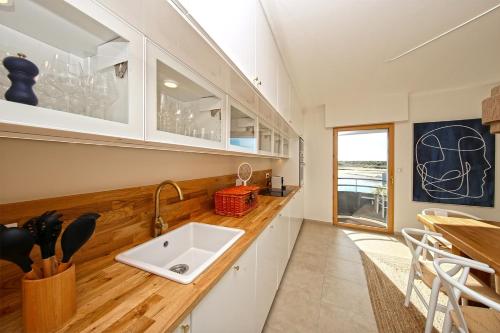 une cuisine avec un évier et un comptoir dans l'établissement La Promenade du Port - Balcon vue sur le port, à Barneville-Carteret