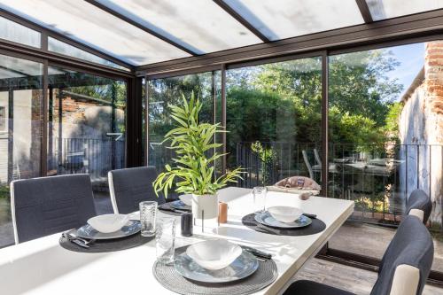 - une salle à manger avec une table, des chaises et des fenêtres en verre dans l'établissement Tranquillité - Maison climatisée avec jardin, à Golfech